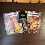 Left to Right: Strongholds & Followers, an EZD6 dice set (with karma tokens), and Kingdoms & Warfare