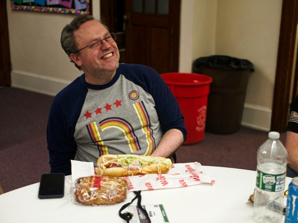 A happy convention-goer eats a wawa hoagie.