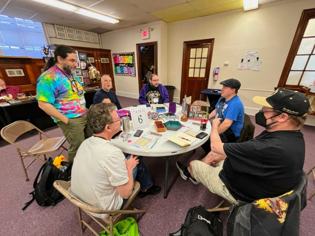 Players at a circular table discuss how to make their next move.
