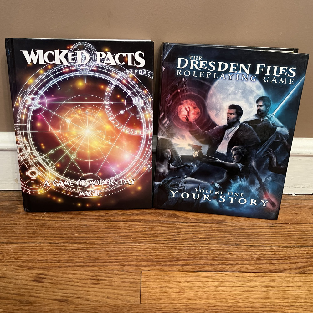 Wicked Pacts and The Dresden Files rulebooks standing next to each other.