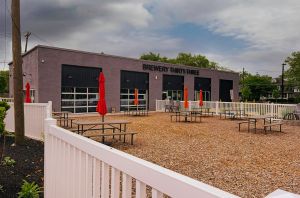 Brewery Thirty-Three outdoor seating out. Several picnic tables on wood chips, surrounded by a white fence.
