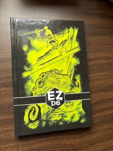 DM Scotty’s new EZD6 horror book, featuring a woman balancing over a horror, sword held above her head.